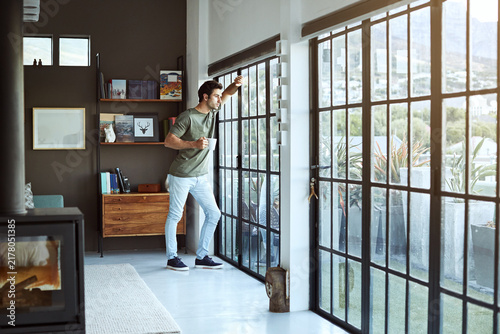фотографія Glass door, man and thinking with coffee in home to start day, check weather and reflection