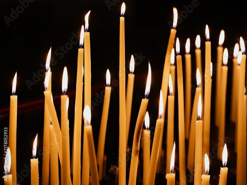 Fotografie Vue rapprochée d'un groupe de cierges verticaux allumés dans un édifice religieux et formant une multitude de flammes créant une ambiance chaleureuse