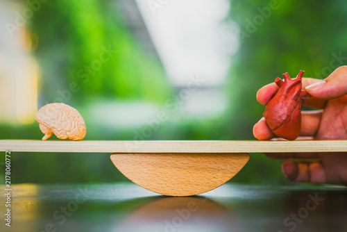 Картината върху платно Brain and heart balance concept with anatomical organ models on wooden seesaw scale against green bokeh background for logic versus emotion, mental health and rational decision making