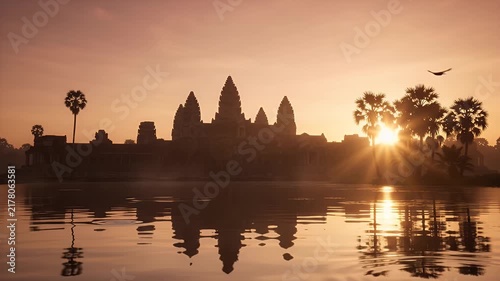 Ancient temple silhouette at sunrise with water reflection