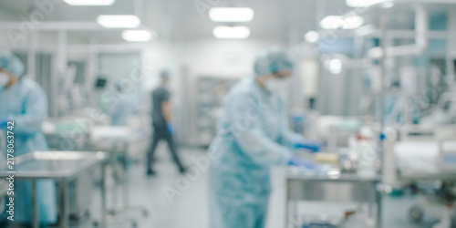 A modern surgical room with professionals in scrubs and masks. Equipment and medical instruments are organized on stainless steel tables, emphasizing a sterile environment.