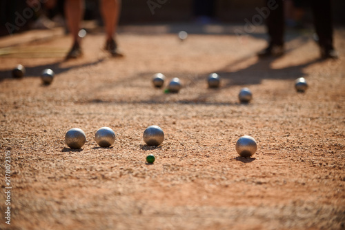 Petanque Boules and Green Jack Target Ball with Players in Background