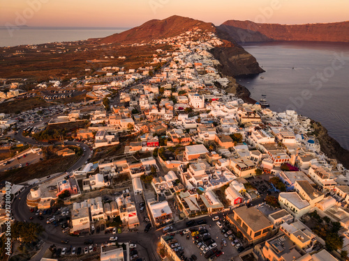 Fotografie Panoramic aerial drone shot of Oia village and caldera coastline glowing at gold