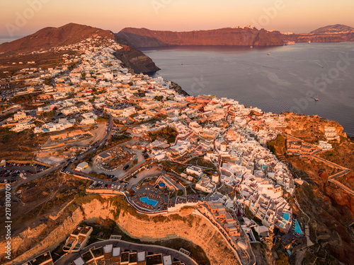 Obraz na płótnie Wide aerial drone perspective of Oia town peninsula and caldera bay at golden su