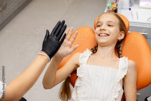 Happy dentist and young girl patient giving high five in clinic