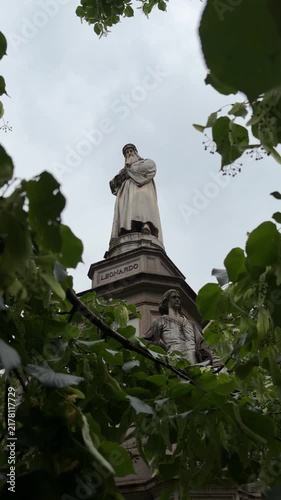 Milan, Italy - May 05, 2026: Leonardo da Vinci statue partially obscured by green leaves in a park, highlighting its artistic features and cultural importance