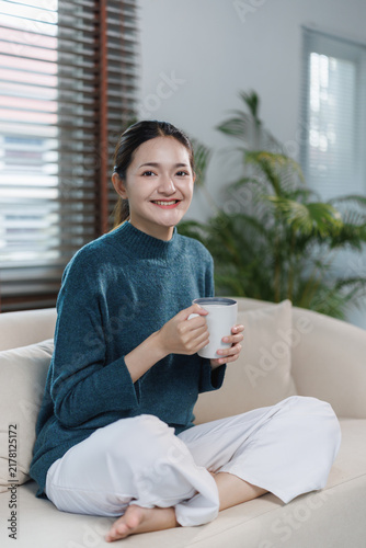 Фотография Asian woman enjoying warm coffee at home