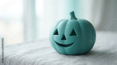 A minimalist teal carved pumpkin figurine decorates a bright indoor surface creating a modern and cheerful seasonal autumn holiday festive display