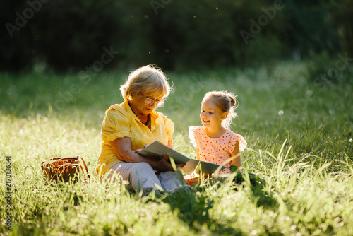 Photography Grandmother reading story to happy granddaughter in park