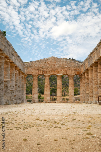 Wide interior perspective view of open courtyard flanked by Doric colonnades leading to end pediment in Segesta, Sicily, Italy