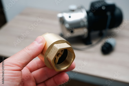 Принти на полотні Hand holding brass check valve with stainless steel surface water pump in backgr