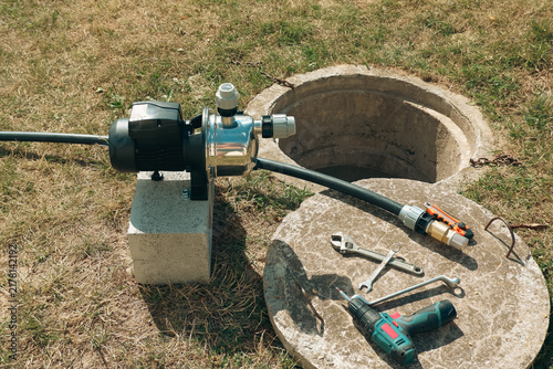 Cuadro en lienzo Tools and suction pipe with brass check valve lying on concrete well cover next