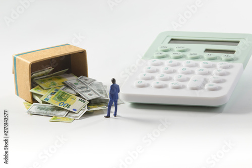 Financial management concept with money spilling from a cardboard box and calculator