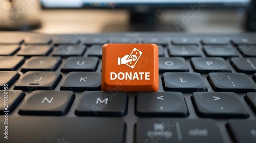 Orange donate button on a black computer keyboard close up with keyboard computer philanthropy