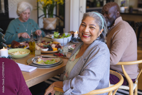 Happy senior woman celebrating with friends at christmas dinner in sunny dining room