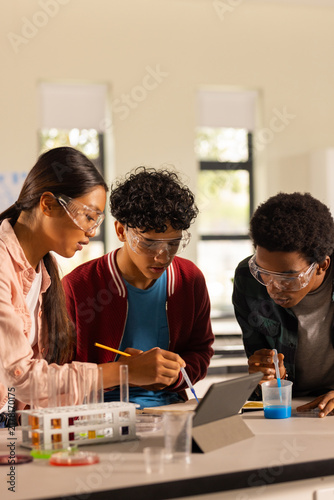 Cuadro en lienzo Conducting science experiment, teenagers using tablet and lab equipment in high