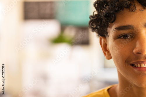 Smiling teenage boy focusing on classroom activities in high school, copy space