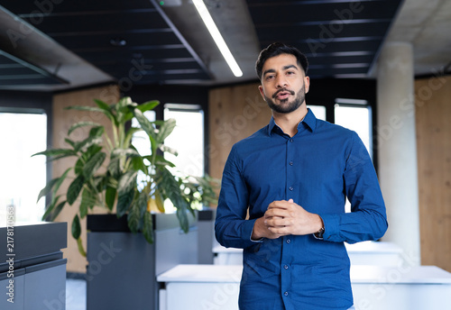 Business professional in modern office standing and speaking confidently to camera
