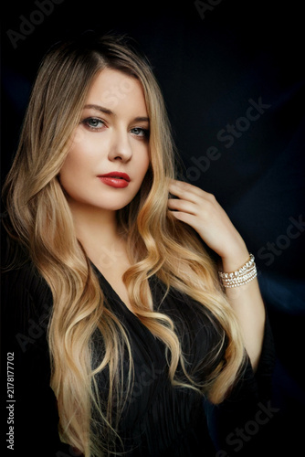 Quadro su tela Blonde woman posing confidently, wearing a black dress and pearl bracelet, showi
