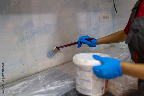 Foto Worker painting wall with brush and blue gloves