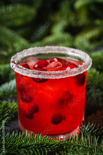 Red christmas cocktail with cranberry juice on the fir branches background. Christmas mood. Selective focus. 
