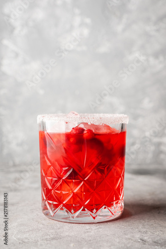 Red christmas cocktail with cranberry juice on the gray concrete background. Christmas mood. Selective focus. 