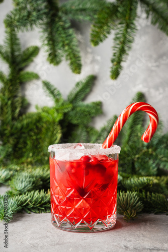 Red christmas cocktail with cranberry juice on the fir branches background. Christmas mood. Selective focus. 