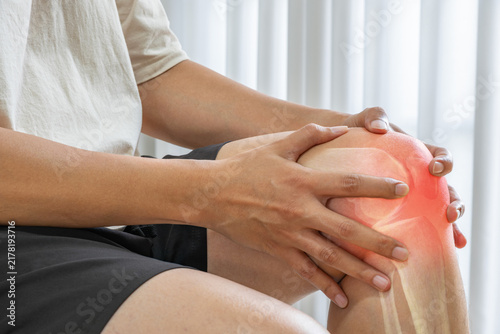 Knee pain shown with a medical anatomy overlay highlighting the patella and knee tendons. The image represents joint inflammation injury and orthopedic treatment.