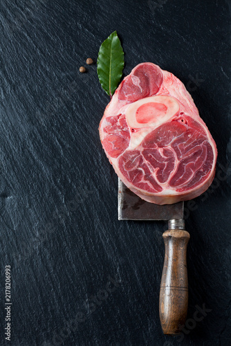 Raw beef shank with bay leaves and allspice on cleaver