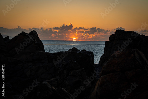 Foto Aerial video along a tropical beach at dawn with golden sunrise over rocks Macka