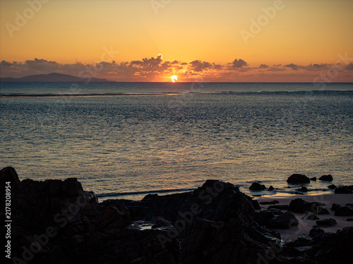 Canvas Print Aerial video along a tropical beach at dawn with golden sunrise over rocks Macka
