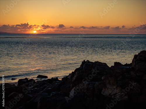 Canvas Print Aerial video along a tropical beach at dawn with golden sunrise over rocks Macka