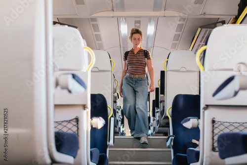 Woman walks down the aisle of an intercity train carriage
