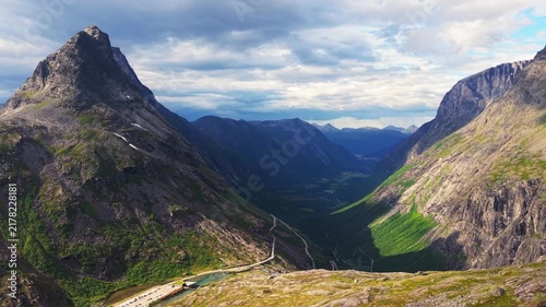 aerial overview of a sharp mountain summit towering over the lush green Trollstigen valley in western Norway