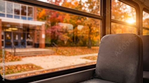 Empty School Bus Seat Overlooking Autumn Campus Through Window At Sunset Commute