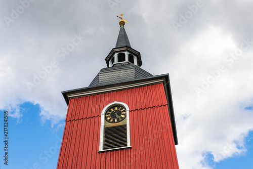 Church tower. Historic wooden red tower of church with a golden clock, black spire and weather vane.