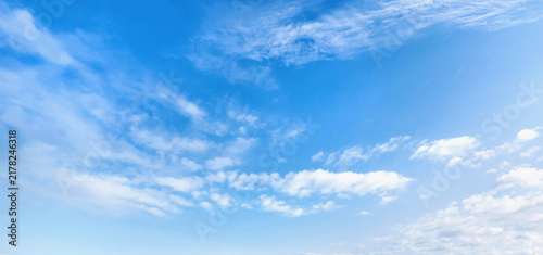 Clear blue sky with wispy white clouds drifting above