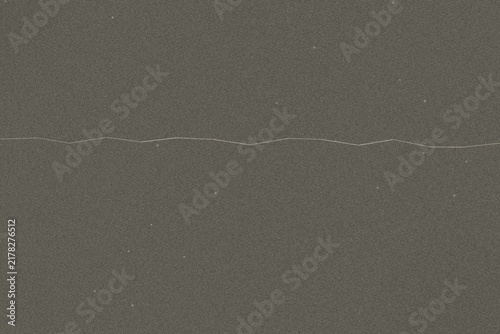 Abstract texture featuring horizontal light streak on dark grey vintage film grain surface.