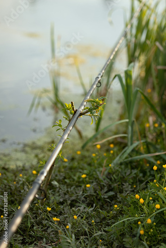 A photo of a fishing rod on the shore of a reservoir.