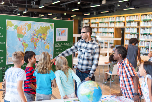 Male teacher instructing diverse elementary students in classroom