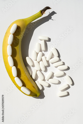 Фотография Ripe banana and white pills isolated on white background for men health potency
