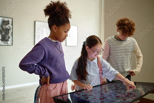 Diverse children looking at interactive screen in art gallery during school field trip. Image represents modern education and interactive learning, perfect for museum marketing