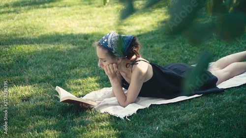 Young woman reading a book on the grass in a park
