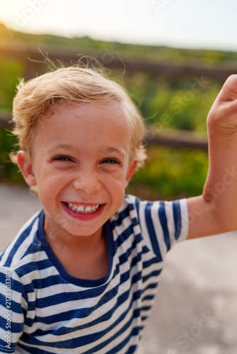 Young boy smiling outdoors during summer vacation, expressing happiness, joy, and positive childhood emotions