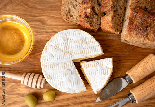 Camembert cheese served with rye bread, honey and olives. Gourmet appetizer for entertaining. Close-up. Top view.