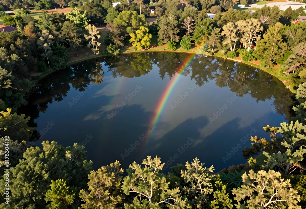 Obraz premium Nature conservation and environmental beauty, double rainbow over a calm forest lake reflecting lush green trees in a peaceful woodland landscape