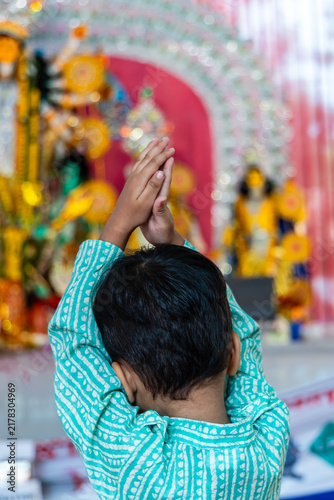 Child Praying Before Goddess Durga Idol During Durga Puja Celebration