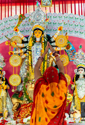 Ornate Hindu Goddess durga Statues During Puja with blurry Woman Offering hand