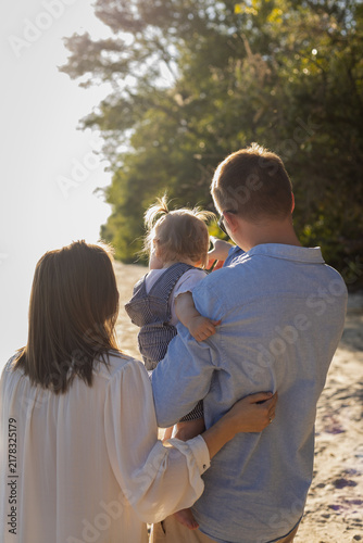 Фотография Family enjoying a sunny day at the beach with their young child