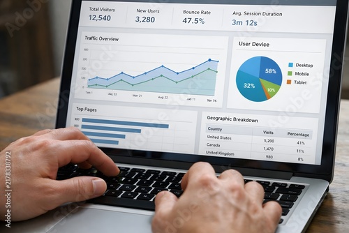 Hands typing on laptop showing website analytics dashboard with charts and data